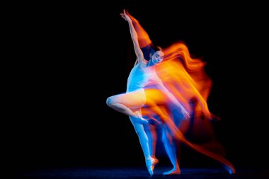Inspiration. Young and graceful female ballet dancer dancing over dark background in mixed neon light. Art, motion, action, flexibility, creativity concept. Moves in fire glow.