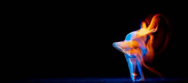 Beauty and grace. Flexible and beautiful girl, ballet dancer in motion over dark background in mixed neon light. Art, motion, action, flexibility, creativity concept. Moves in fire glow.