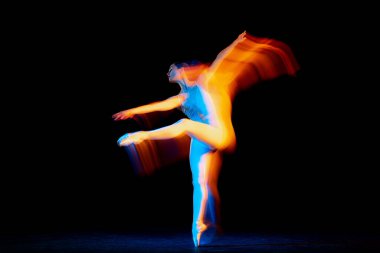Inspiration. Young and graceful female ballet dancer dancing over dark background in mixed neon light. Art, motion, action, flexibility, creativity concept. Moves in fire glow.