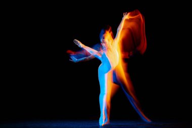 Beauty and grace. Flexible and beautiful girl, ballet dancer in motion over dark background in mixed neon light. Art, motion, action, flexibility, creativity concept. Moves in fire glow.
