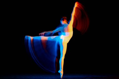 Beauty and grace. Flexible and beautiful girl, ballet dancer in motion over dark background in mixed neon light. Art, motion, action, flexibility, creativity concept. Moves in fire glow.