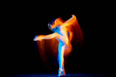 Inspiration. Young and graceful female ballet dancer dancing over dark background in mixed neon light. Art, motion, action, flexibility, creativity concept. Moves in fire glow.
