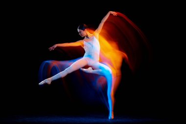 Dynamic portrait of tender slim girl, female ballet dancer in art performance isolated over black background in mixed bright neon light. Art, motion, action, flexibility, creativity and ad concept.