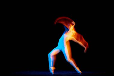 Ease of movement. Tender female ballet dancer dancing solo dance over dark background in mixed neon light. Art, flexibility, inspiration and beauty concept. Moves in fire glow. Copy space for ad