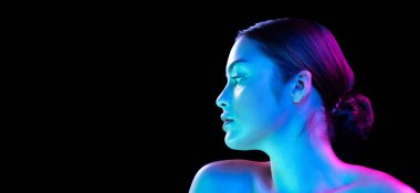Charm, flirt. Young beautiful girl with well-kept skin and without makeup isolated over dark background in neon light. Concept of natural beauty, art, emotions, cosmetics and youth. Flyer for ad