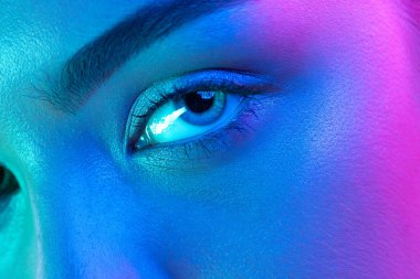 Blue eyes. Close up eyes of beautiful young girl looking camera in pink neon light. Concept of cosmetics, makeup, natural and eco treatment, skin care. Shiny and healthy look, fashion, vision. Details