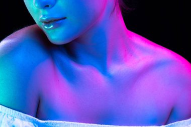 Close up female neck, collarbones and shoulders in pink neon light over dark background. Beautiful young womans body with well-kept skin. Beauty, fitness, plastic surgery and aesthetic cosmetology