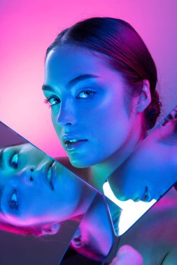 Feeling and emotions. High fashion model in colorful bright neon lights posing at studio. Portrait of beautiful girl with glowing make-up. Art design vivid style. Spa, cosmetics, beauty procedures