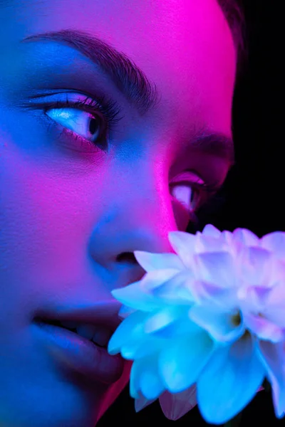 Blue eyes. Close up eyes of beautiful young girl looking camera in pink neon light. Concept of cosmetics, makeup, natural and eco treatment, skin care. Shiny and healthy look, fashion, vision. Details