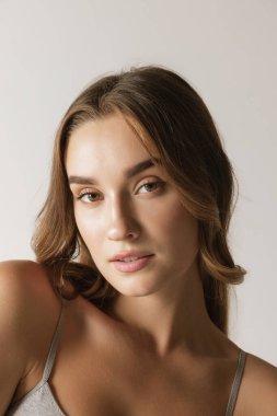 Closeup portrait of young cheerful beautiful girl with curly long hair smiling and looking at camera with happy and relaxed face expression. Health, beauty, fashion and ad concept