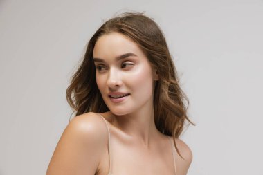 Closeup portrait of young cheerful beautiful girl with curly long hair smiling and looking at camera with happy and relaxed face expression. Health, beauty, fashion and ad concept