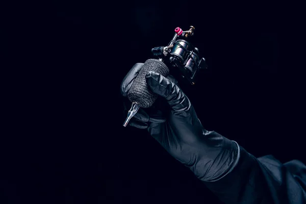 タトゥーのためのマシン 暗い背景に隔離された体に入れ墨を作るための専門的な機器を保持している黒の保護手袋の人間の手 アート 広告ポスターのコンセプト — ストック写真