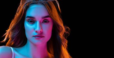 Gurur. Genç, kıvırcık, uzun saçlı, neon ışıkta siyah zeminde izole edilmiş güzel bir kız. Mutlu ve rahat görünüyor. Sağlık, güzellik, moda ve reklam konsepti. - Yakın çekim. İlan için alanı kopyala