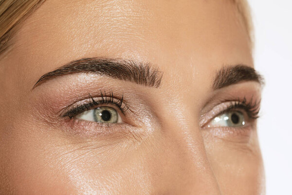 Зеленые глаза и идеальные формы бровей. Закройте лицо красивой молодой девушки, смотрящей в камеру. Концепция косметики, косметики, натурального и эко-лечения, ухода за кожей. Блестящий и здоровый вид. Подробности.