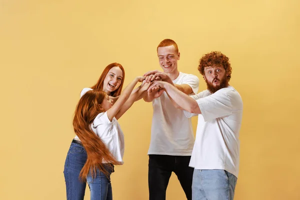 Support. Group of different ages redhead people wearing white tees and jeans posing isolated on yellow background. Emotions, friendship and active lifestyle. Look happy, delighted and cute