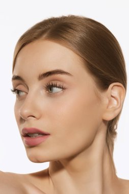 Mükemmel özellikler. Beyaz arka planda, iyi korunmuş derisi ve açık renkli günlük makyajı olan güzel bir kızın portresi. Güzellik, kaplıca, kozmetik, yüz gerdirme ve cilt bakımı konsepti. Yakın çekim.