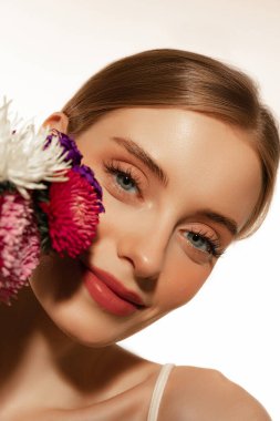 Mükemmel özellikler. Beyaz arka planda, iyi korunmuş derisi ve açık renkli günlük makyajı olan güzel bir kızın portresi. Güzellik, kaplıca, kozmetik, yüz gerdirme ve cilt bakımı konsepti. Yakın çekim.