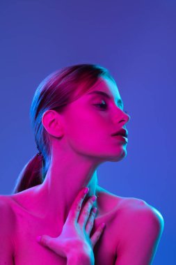 İlham. Genç ve güzel bir manken. Cildi bakımlı ve omuzları çıplak. Pembe neon ışıkta koyu arka planda izole edilmiş. Canlı stil, güzellik, sanat, gelecek konsept.