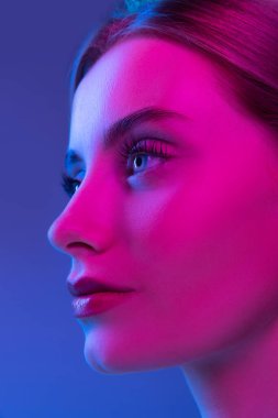 Pembe neon ışıkta koyu bir arka planda iyi korunmuş genç ve güzel bir kızın yakın profil görüntüsü. Moda anlayışı, duygular, tarz, ilham. Resim.