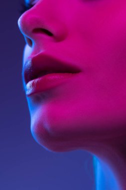 Smile. Closeup female lips, cheeks and nose isolated over dark background in neon light. Natural beauty. Concept of natural beauty, cosmetology, skincare, cosmetics, plastic surgery, ad