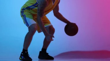- Yakın çekim. Stüdyoda basketbol topu eğitimi almış profesyonel bir basketbolcu. Gradyan mavi neon arka planda. Spor, aksiyon, hareket, yetenek konsepti. Yavaş çekim etkisi