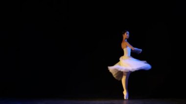 Genç ve zarif klasik bale dansçısı beyaz elbiseli kadın koreografi dersinde siyah arka planda dans ediyor. Klasik sanat, güzellik, zarafet ve zerafet kavramı