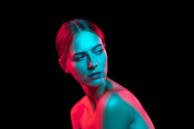Koyu arkaplanda kırmızı ışıklı çıplak omuzlu güzel bir kadının yakın plan portresi. Sanat, yaratıcılık, moda, tarz. Ciddi ve düşünceli bir model.