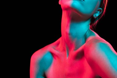 Kadın boynunu, köprücük kemiklerini ve omuzlarını koyu arkaplan üzerinde kırmızı neon ışıkla kapat. İyi korunmuş ciltli güzel bir genç kadın vücudu. Güzellik, zindelik, estetik cerrahi ve estetik kozmetoloji