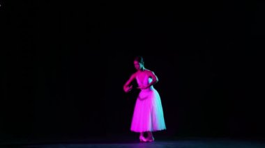 Genç, güzel bir kadın, beyaz elbiseli kadın balerin klasik bale öğeleri yapıyor. Yumuşak ve zarif görünüyor. Sanat, güzellik, müzik ve hareketlerdeki zarafet kavramı