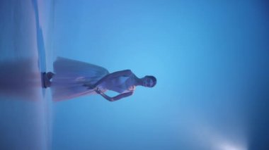 Genç, güzel bir kadın, beyaz elbiseli kadın balerin klasik bale öğeleri yapıyor. Yumuşak ve zarif görünüyor. Sanat, güzellik, müzik ve hareketlerdeki zarafet kavramı