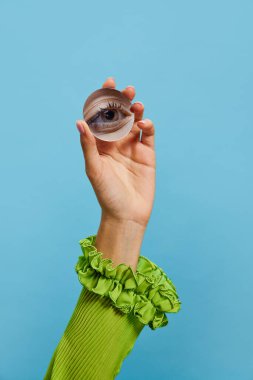 - Yakın çekim. Mavi arka planda izole edilmiş kızların gözünün yansıması olan küçük bir ayna tutan bir kadın el. Klasik moda, güzellik, sanat, yaratıcılık ve reklam kavramı. İnsani duygular, yüz ifadesi