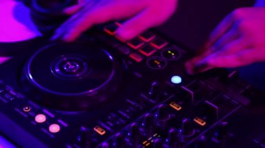 Derin vuruşlar. DJ yapımcısının ellerinin gece kulübü partisinde ses çıkardığı ve profesyonel ses mikserinin neon ışıkta yandığı yakın çekim görüntüsü. Modern parti tarzı. Müzik kavramı, eğlence, gençlik kültürü, keyif