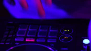Derin vuruşlar. DJ yapımcısının ellerinin yakın plan görüntüsü neonlu profesyonel ses mikseriyle gece kulübü partisinde ses çıkarıyor. Modern parti tarzı. Müzik kavramı, eğlence, gençlik kültürü, keyif, yaşam tarzı