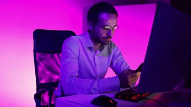 Olgun iş adamı bilgisayarda oturuyor, telefon kullanıyor, daktilo kullanıyor, bilgisayar ekranına bakıyor, gözlüklere yansıyor. Düşünüyorum, finansal dijital verileri analiz ediyorum. Uzak çalışma, iş, finans