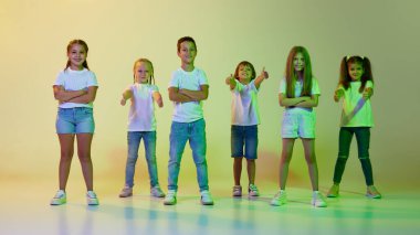 Sokak tarzı. Şık çocuklar, günlük kıyafetlerle dans eden küçük kızlar ve oğlanlar yeşil arka planda sarı neon ışıkta izole edilmiş hip-hop dansı yapıyorlar. Müzik kavramı, moda, sanat, modern düşünce dansı