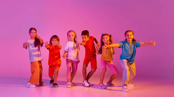 现代编舞 在霓虹灯下 一群快乐 穿着鲜艳衣服的男孩和女孩在粉色背景下孤立无援地跳舞 爱好的概念 — 图库照片