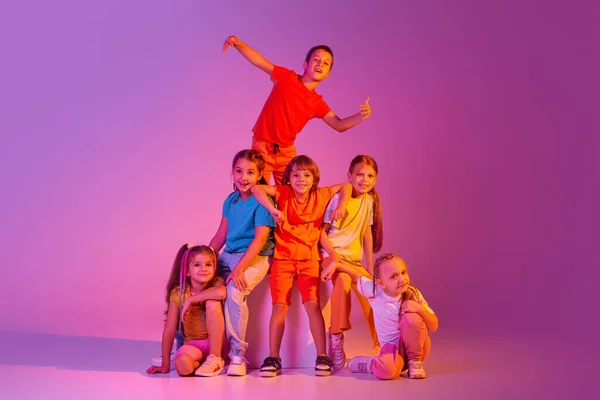 现代编舞 在霓虹灯下 一群快乐 穿着鲜艳衣服的男孩和女孩在粉色背景下孤立无援地跳舞 爱好的概念 — 图库照片