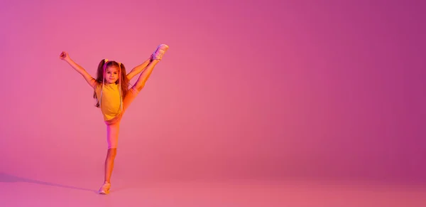 白人の少女の肖像画 ネオンでピンクの背景に孤立して踊るカジュアルな明るい服の子供 子供の感情 ニュース 子供時代 教育の概念 広告のコピースペース — ストック写真