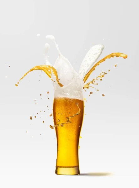 Foam and beer splashes from full glass of frothy light lager beer isolated over light background. Concept of alcohol, oktoberfest, drinks, holidays and festivals. Copy space for ad.