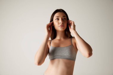 Gri stüdyo arkaplanından izole edilmiş pamuklu bluzla poz veren genç kadının portresi. Kadın kozmetoloji tedavisi. Güzellik, vücut ve cilt bakımı, sağlık, estetik cerrahi, kozmetik