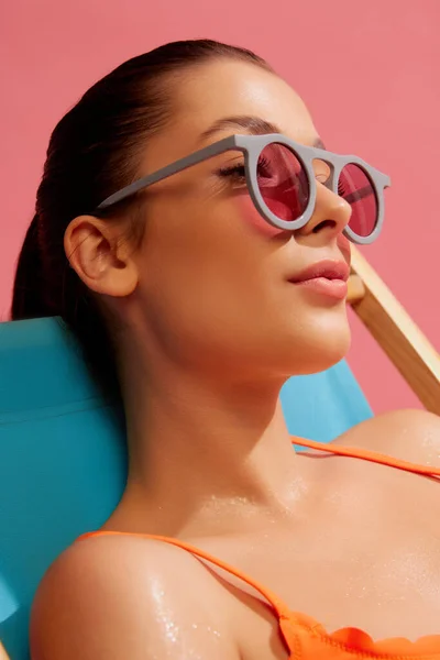 분홍색 배경으로 고립된 선글라스를 아름다운 여성의 Spf 아름다움의 우주론 수영복 — 스톡 사진