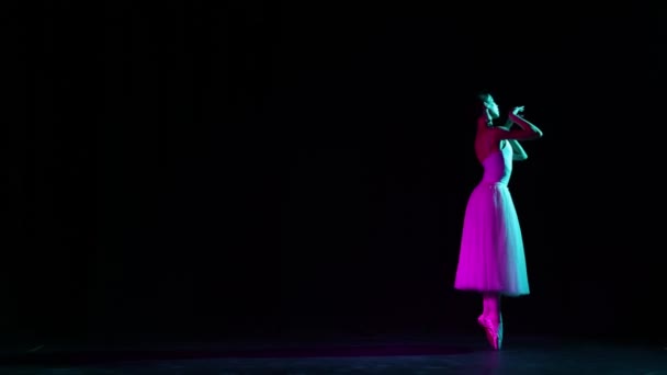 艳丽的芭蕾舞女舞者在霓虹灯下的黑暗舞台上独自跳舞 艺术的概念 古典音乐 美丽的芭蕾舞演员穿着尖皮鞋在聚光灯下跳舞 — 图库视频影像
