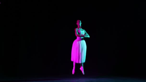 艳丽的芭蕾舞女舞者在霓虹灯下的黑暗舞台上独自跳舞 艺术的概念 古典音乐 美丽的芭蕾舞演员穿着尖皮鞋在聚光灯下跳舞 — 图库视频影像