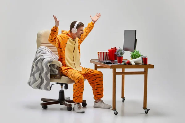 灰色の背景の上に隔離された自宅のコンピュータ机に座っている虎の驚くべき衣装の怒っている若い男 アート アイデア 創造性 休日のコンセプト — ストック写真