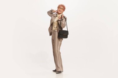 Mutlu görünüyor, mutlu. Beyaz arka planda izole edilmiş eski moda kıyafetlerle şık bir son sınıf kadınının stüdyo fotoğrafı. Güzellik anlayışı, eski nesil, tarz, duygu. İlan için alanı kopyala
