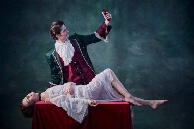 Ortaçağ vampirinin portresi masada yatan ölü kadının selfie 'sini çekiyor koyu yeşil arka plan üzerinde. Kurban. Cadılar Bayramı kavramı, gizem, gotik sanat, fantezi, gerçeküstü karakterler.