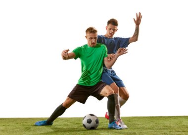 Top için yoğun bir mücadele. İki futbolcu iş başında, yeşil çimlerde hareketli beyaz arka planda izole edilmiş. Spor anlayışı, aksiyon, rekabet, futbol maçı. Futbol oynayan sporcular