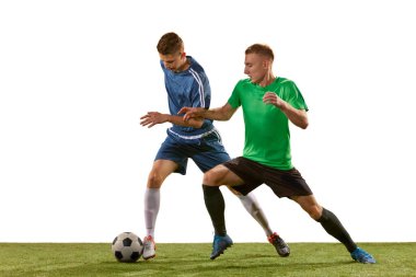 Futbol oyuncuları beyaz arka planda çimlerin üzerinde top oynuyorlar. Spor anlayışı, aksiyon, rekabet, futbol maçı. Sporcular iş başında, hareketler oyunda.