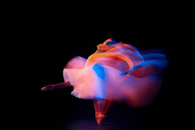 Fütürizm, fantezi, mucize. Zarif ve narin balerin, bale elbisesi içinde, siyah arka planda, karışık neon ışıkta izole edilmiş. Sanat, güzellik, eylem, esneklik, yaratıcılık ve reklam kavramı.