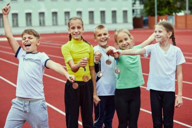 Zaferi kutlayan bir kız ve erkek. Motive çocuk takımı ellerini kaldırsın. Spor yapan mutlu çocuklar. Kazanma, spor, öğrenim, başarılar, başarı kavramı. Takım çalışması, arkadaşlık ve destek